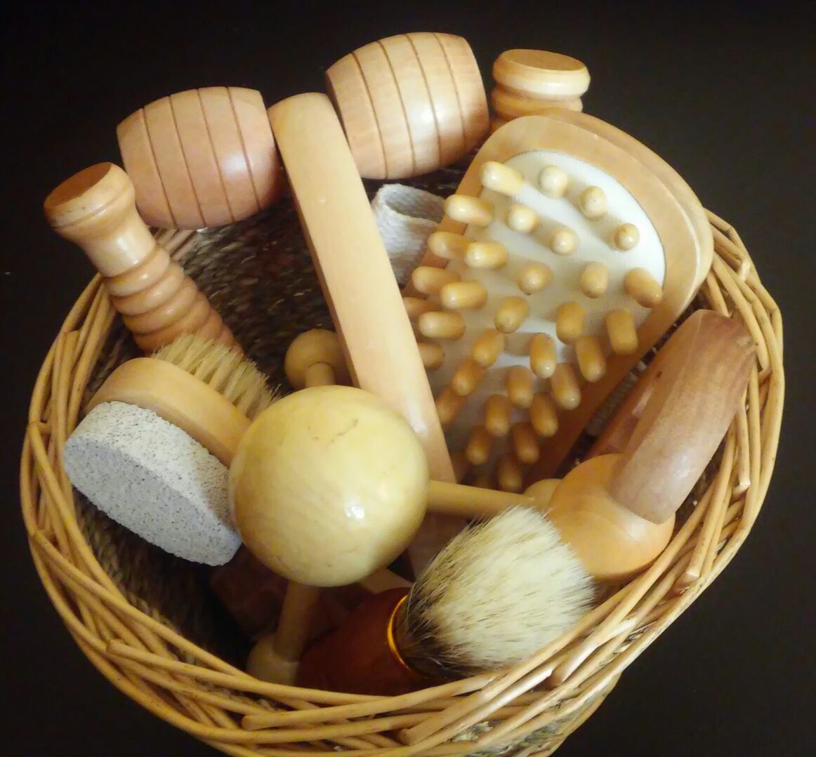 A collection of wooden massage tools and brushes in a woven basket.